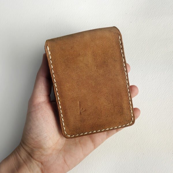 The back of the vintage brown leather playing cards case, held in hand.