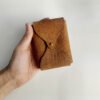 Vintage brown leather playing card case, held in hand.