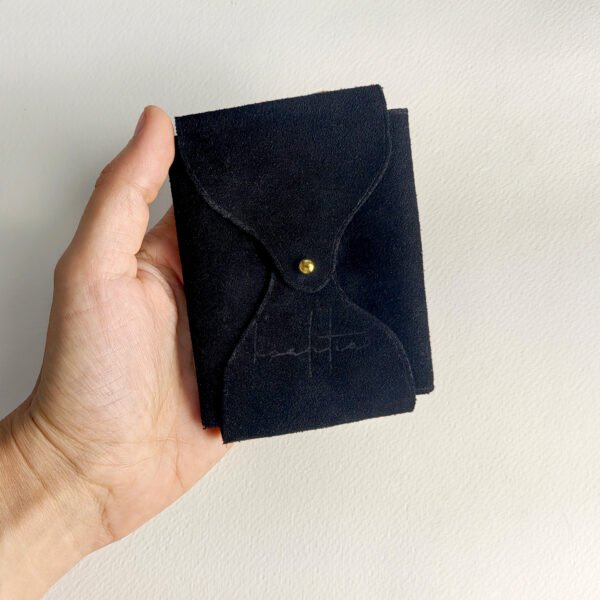 Black velour leather playing card case, held in hand.